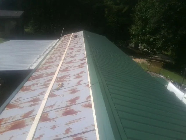 Old rusted panels beside newly installed green metal roofing — Wind Damage Roof Repair by Roofing Brothers in Richmond Hill