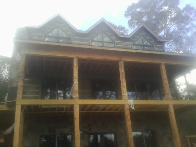 Dormers and porch framing on a large log home under construction — Roof Coating work by our crew in Richmond Hill