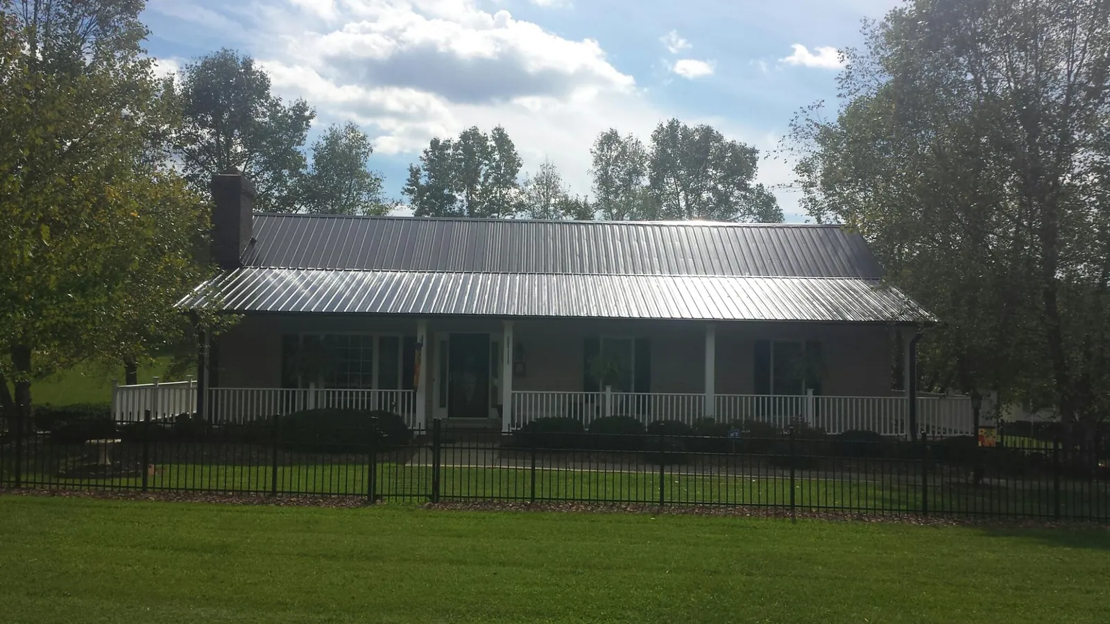 Gray metal roof on a brick ranch with a full width front porch — Gutter Guard Installation work by our crew in Richmond Hill